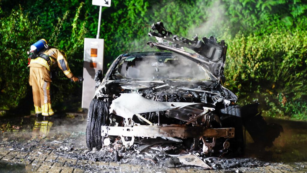 Auto volledig in lichterlaaie op parkeerplaats voor elektrische auto's