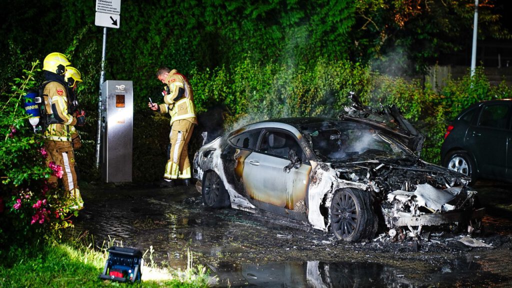 Auto volledig in lichterlaaie op parkeerplaats voor elektrische auto's