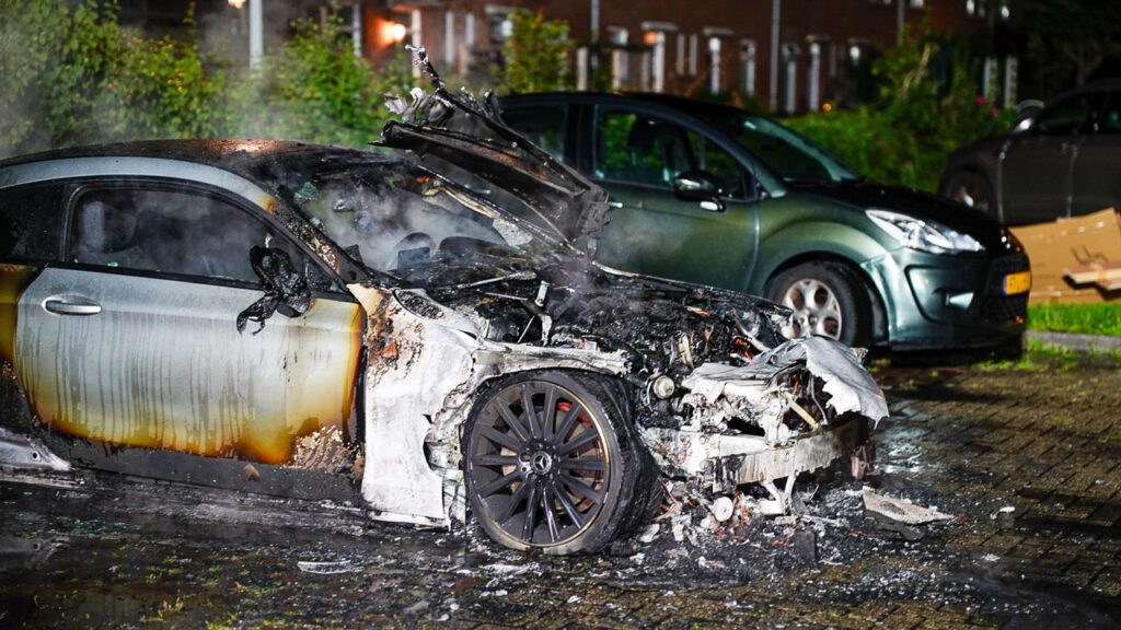 Auto volledig in lichterlaaie op parkeerplaats voor elektrische auto's