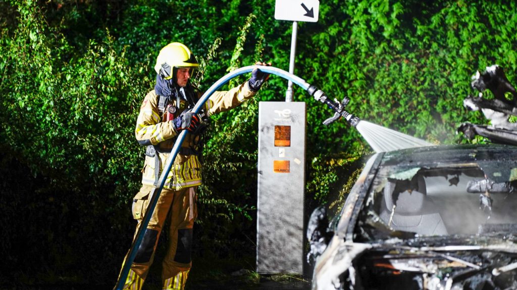 Auto volledig in lichterlaaie op parkeerplaats voor elektrische auto's