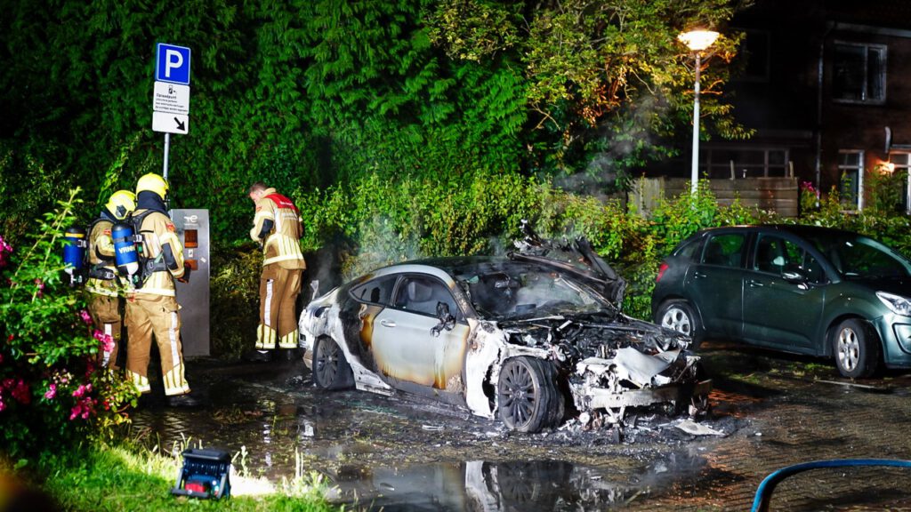 Auto volledig in lichterlaaie op parkeerplaats voor elektrische auto's