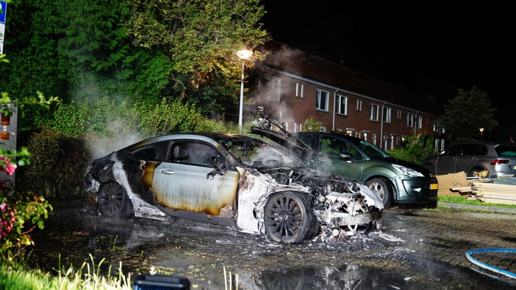 Auto volledig in lichterlaaie op parkeerplaats voor elektrische auto's